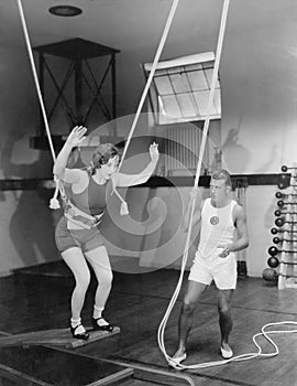 Female gymnast training with safety ropes with coach