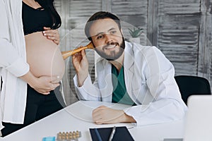 Female gynecologist working with pregnant woman in clinic. Doctor listening to heartbeat of patient