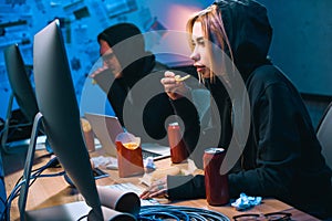 female hacker working on malware with accomplice and eating