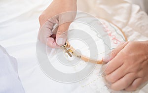 Female had holding wood embroidery frame and preparing work on white cotton in a process of handiwork