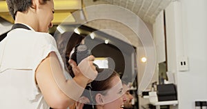 Female hairdresser blow drying her client hair