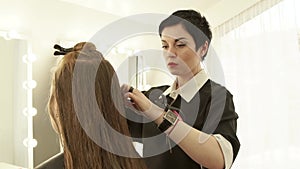 Female hairdresser combing long hair for woman haircut front mirror in beauty salon. Close up haircutter parting hair