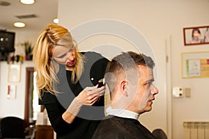 Female hairdresser cutting hair of smiling man client at beauty