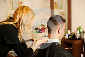 Female hairdresser cutting hair of smiling man client at beauty