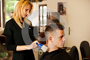 Female hairdresser cutting hair of smiling man client at beauty