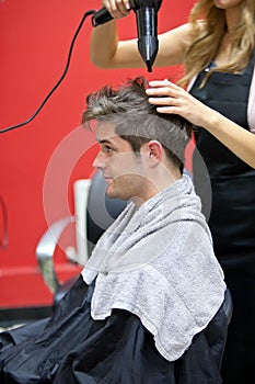 Female hairdresser drying her male customer hair