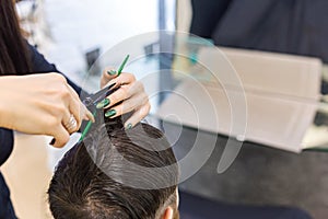 Female hairdresser hands doing haircut for male client using professional hairdresser tools scissors, brush on hairdresser work
