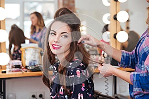 Female hairdresser making hairstyle to cute woman in beauty salon