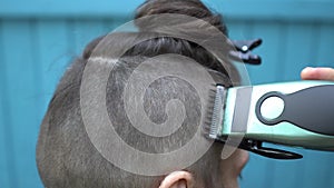 Female hairdresser making male haircut with hair clipper in hairdressing salon on open air Back view Close up