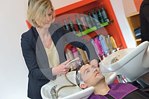 Female hairstylist hairdresser washing male customers hair