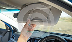 Female hand adjusting sun visor in a car