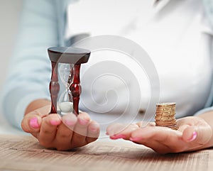 Female hand&#39;s with hourglass and coin. photo