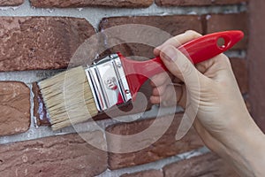 Female hand applying varnish to a decorative plaster tile.