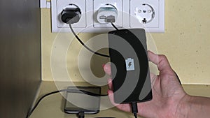 Female hand attach smart phone to wall charger and hold