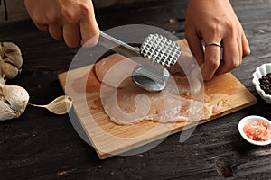 Female Hand Beat Chicken using Meat Tenderizer