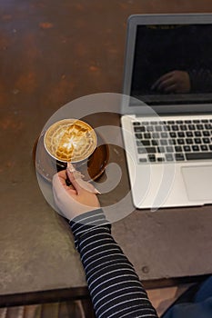 Female hand with beautiful nails holding cup of well-garnished coffee cup