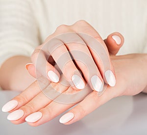 Female hand with beige nail design.