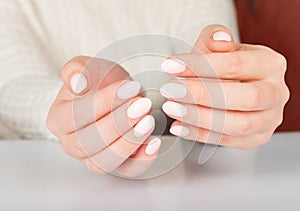 Female hand with beige nail design.