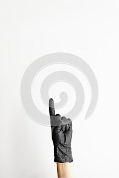 Female hand in black latex gloves pointing from down to free space for text, on white background vertical orientation