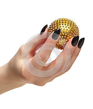 Female hand with black nails manicure and golden spiked massage ball in fingers