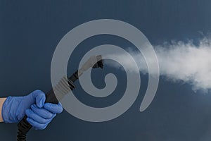 Una mujer mano en azul guantes sostener mangueras cepillar de vapor generador sobre el azul 