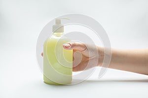 Female hand and bottle with dispenser with yellow liquid soap antiseptic standing on the table on a white background. Horizontal