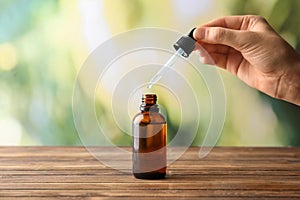 Female hand and bottle with eucalyptus essential oil on blurred background