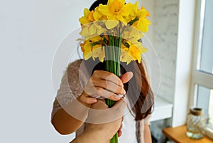 Female Hand With A Bouquet Of The Yellow Narcissuses On White Background.