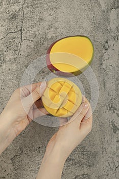 Female hand breaking exotic mango fruit on marble surface