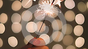 Female hand with burning sparkler in Christmas and New Year holidays.