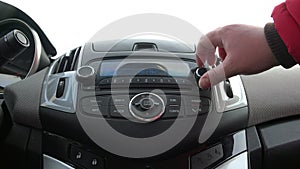 Female hand on the car radio tunes to radio and the radio searches for the display