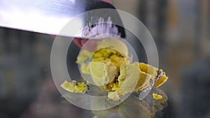 female hand carelessly crumbles and cuts macarons with french dessert with a knife on a glass table close-up yellow