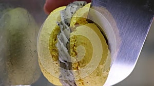 female hand carelessly crumbles and cuts macarons with french dessert with a knife on a glass table close-up yellow