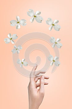 female hand of a Caucasian girl on a gentle background of peach fuzz and flying flowers dogwood. Display for advertising