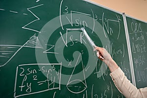 female hand with chalk and write math formula on blackboard