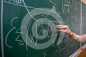 female hand with chalk and write math formula on blackboard