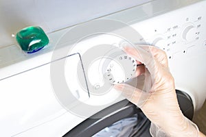 Female hand chooses the washing mode on the washing machine
