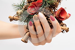 Female hand with Christmas nail design. Red and gold nail polish manicure. Female hand hold New Year decoration