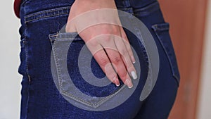 Female hand climbs into the pocket of jeans on the ass