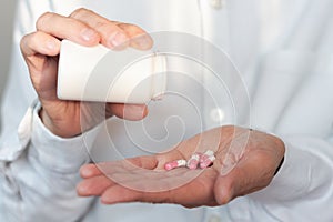 Female hand close up holding a medicine, elderly woman hands with pill on spilling pills out of bottle