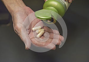 Female hand close up holding a medicine, elderly woman hands with pill on spilling pills out of bottle.