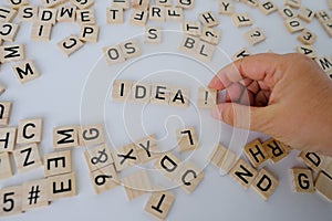 female hand close-up holds wooden alphabet blocks, IDEA word on white background, concept of innovative idea contains creative