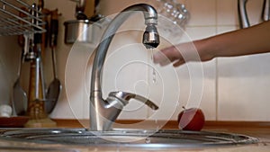 Female Hand Closes Leaking Water Tap. Woman Hits Faucet with Fingers. Close up