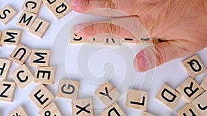 female hand closeup holds wooden alphabet blocks on background, changes word stress to distress, concept transient negative