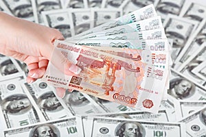 Female hand with cluster of roubles on a background of dollars.