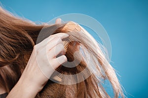 Female hand combing hair with wooden comb