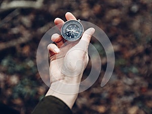 Female hand with compass on background of forest, point of view