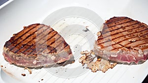 Female hand covers tuna steak with soy sauce with silicone kitchen brush on pan