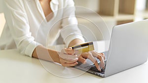 Female hand with credit card and typing on laptop keyboard while online shopping at home