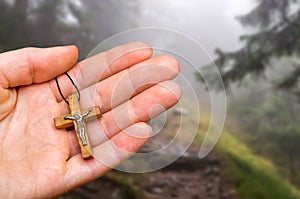 Female hand with cross on haunted forest background
